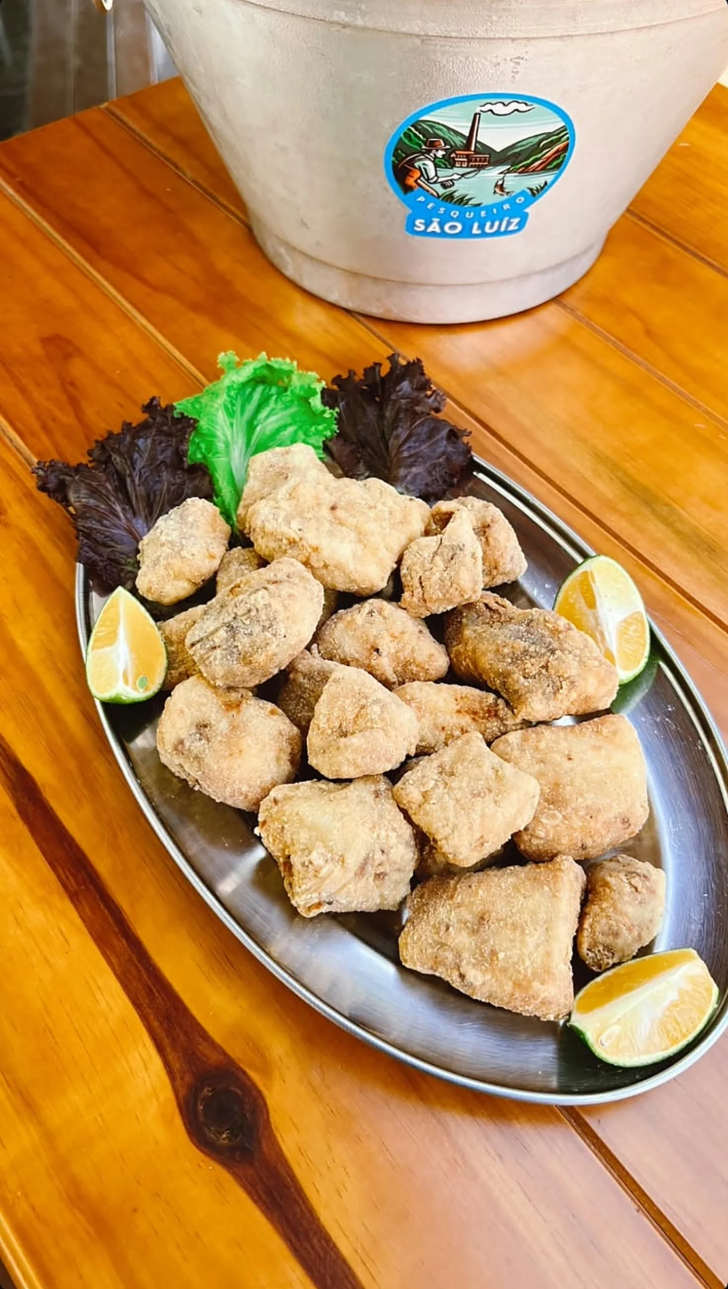 Bandeja de petiscos fritos com limão ao lado do balde do São Luiz